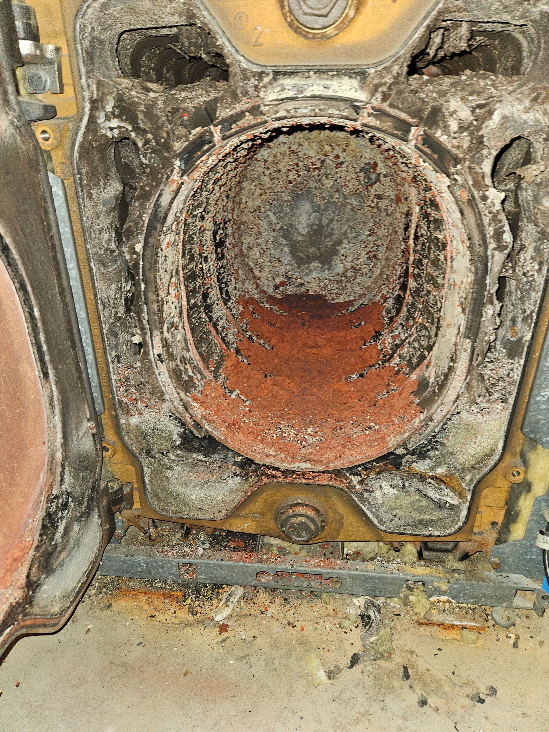 Un gros plan de l'intérieur d'une vieille chaudière avec de la rouille qui en sort.