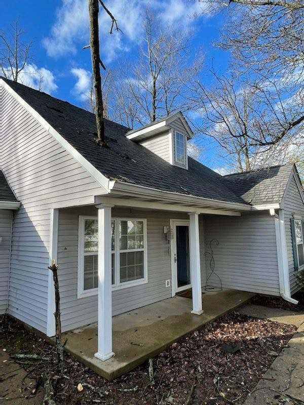 Small white house exterior with a covered porch and blue sky above