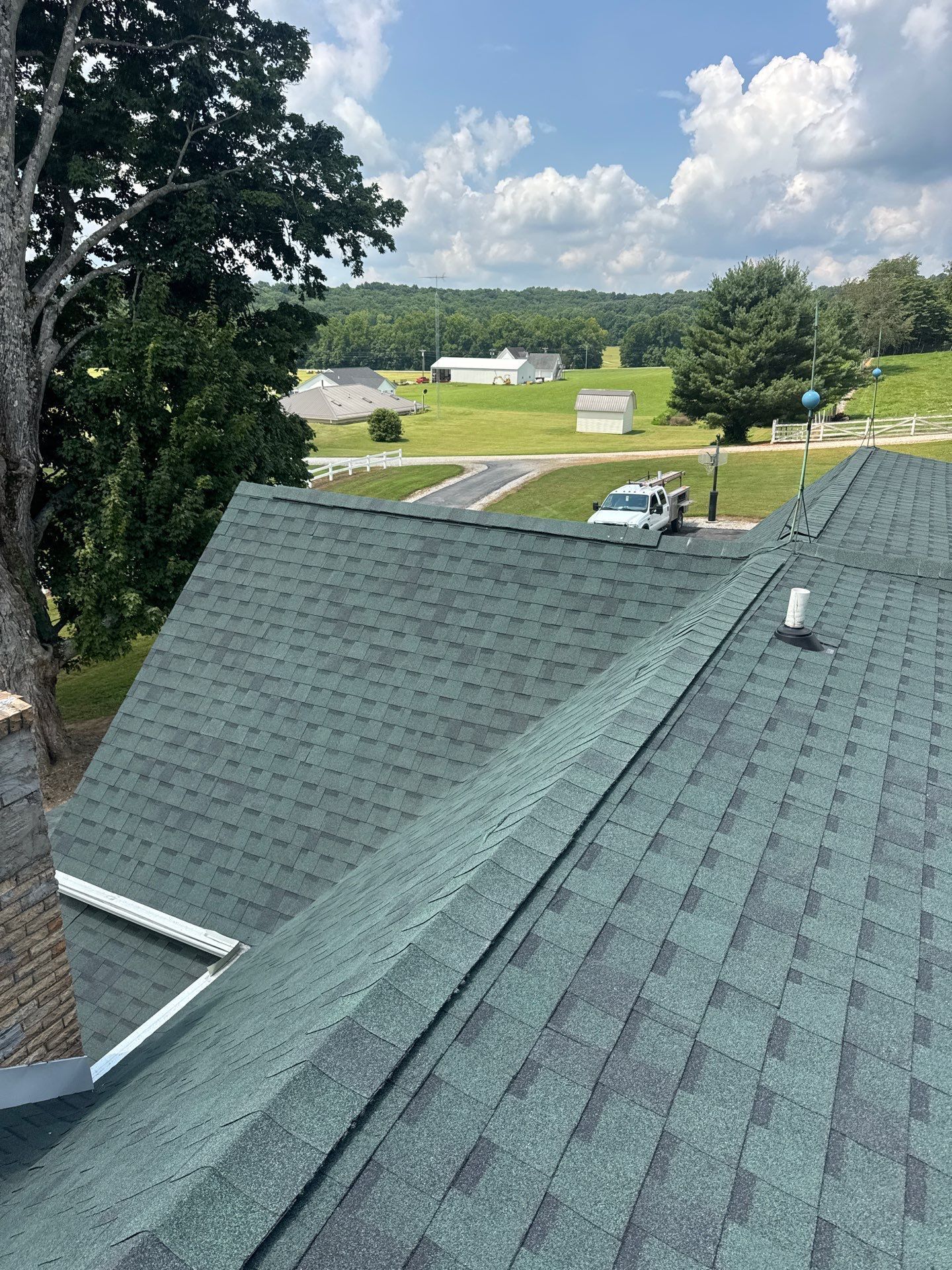 Green shingled rooftops in a suburban neighborhood under a partly cloudy sky.