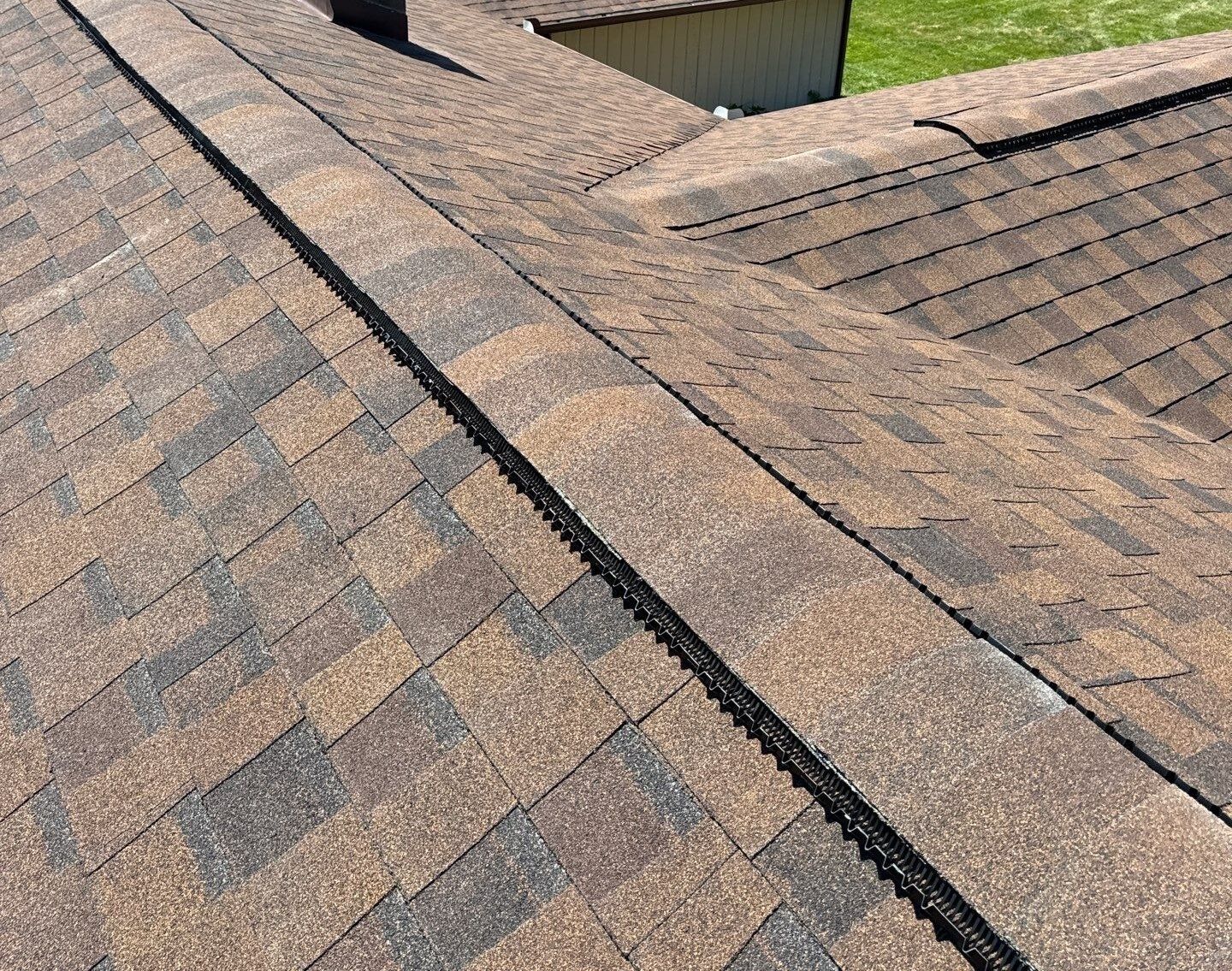 Close-up of a shingled roof with a ridge vent running diagonally across it.