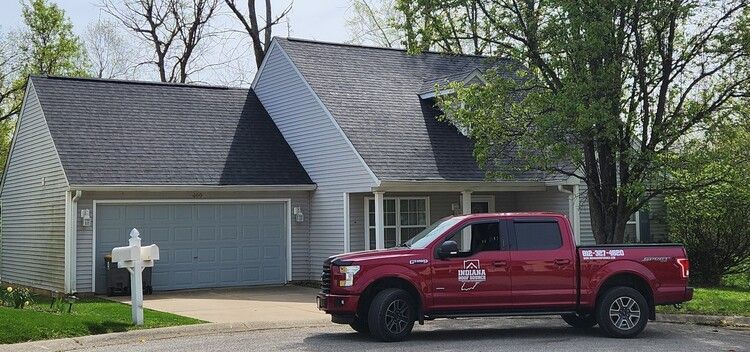 Red pickup truck parked in front of a gray suburban house with a garage and white mailbox