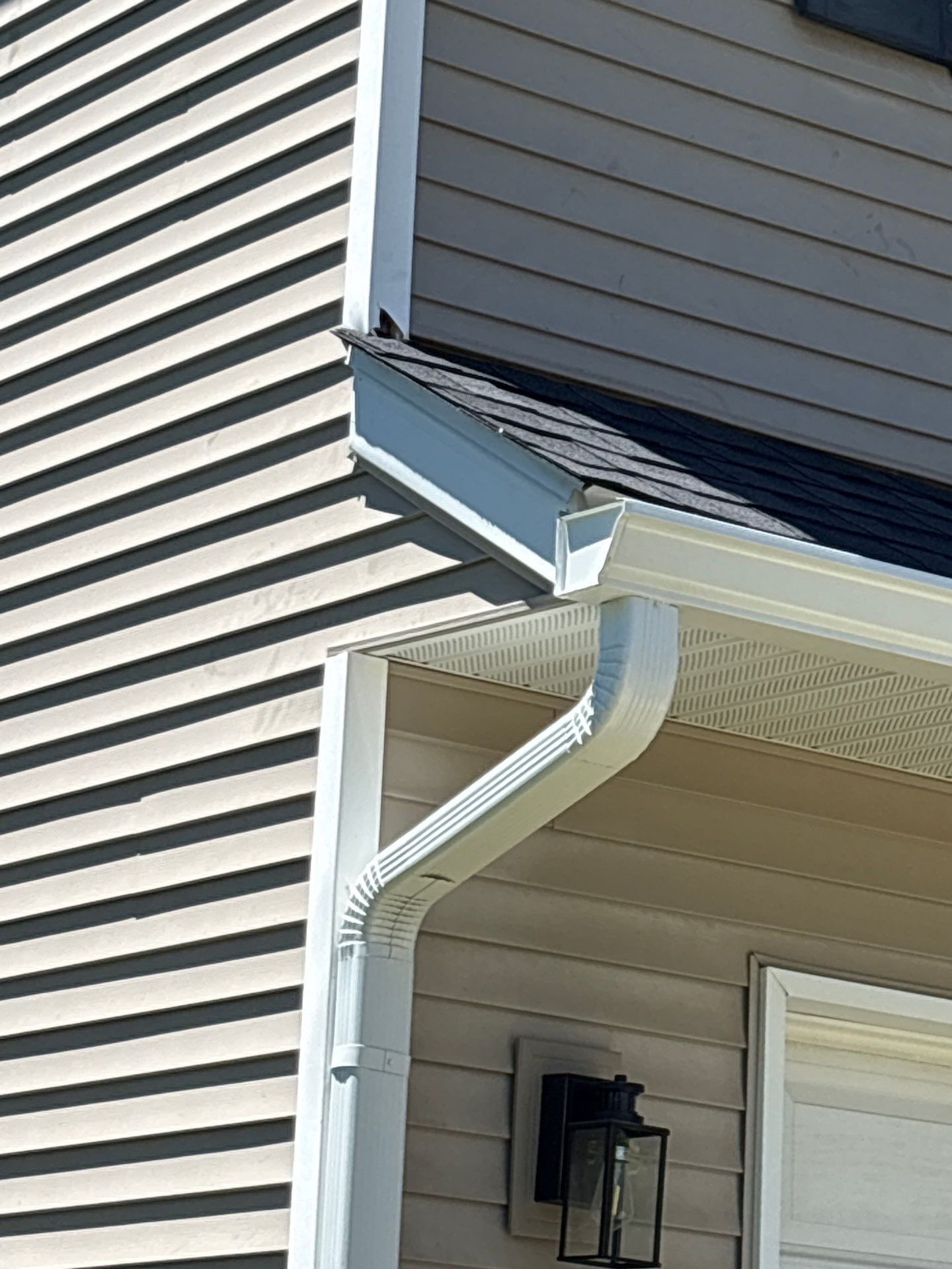 Damaged roof corner with bent gutter and white siding on a house