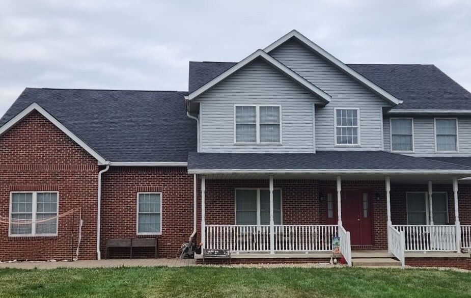 Suburban brick-and-gray house with a covered front porch and neatly trimmed lawn