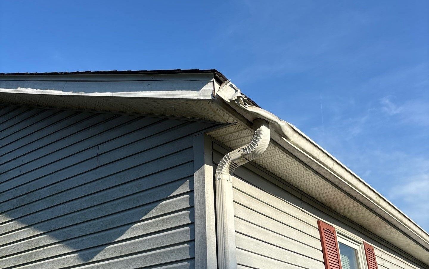 Crushed gutter corner and bent downspout elbow ready for replacement