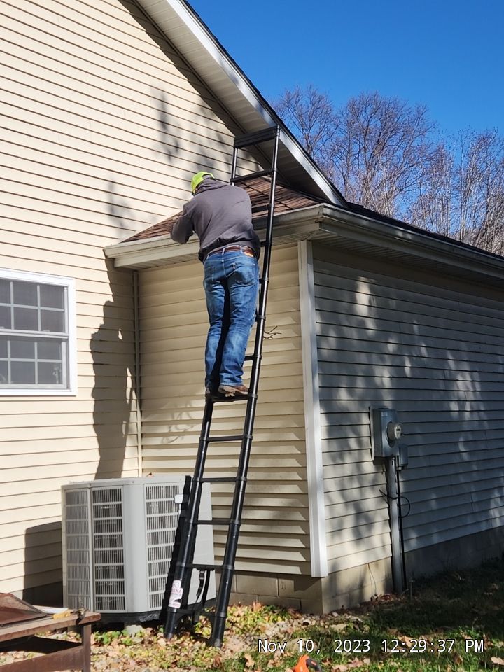 Indiana Roof Source technician on a ladder working along a gutter line