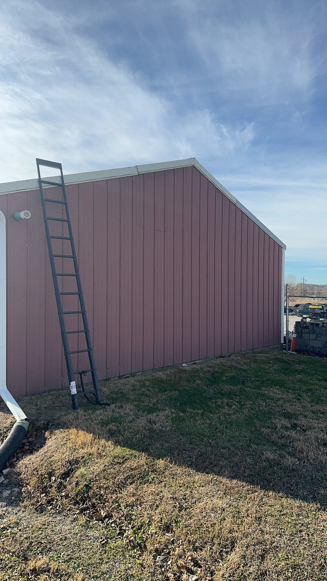 Pink shed with a ladder leaning against the side under a blue sky.