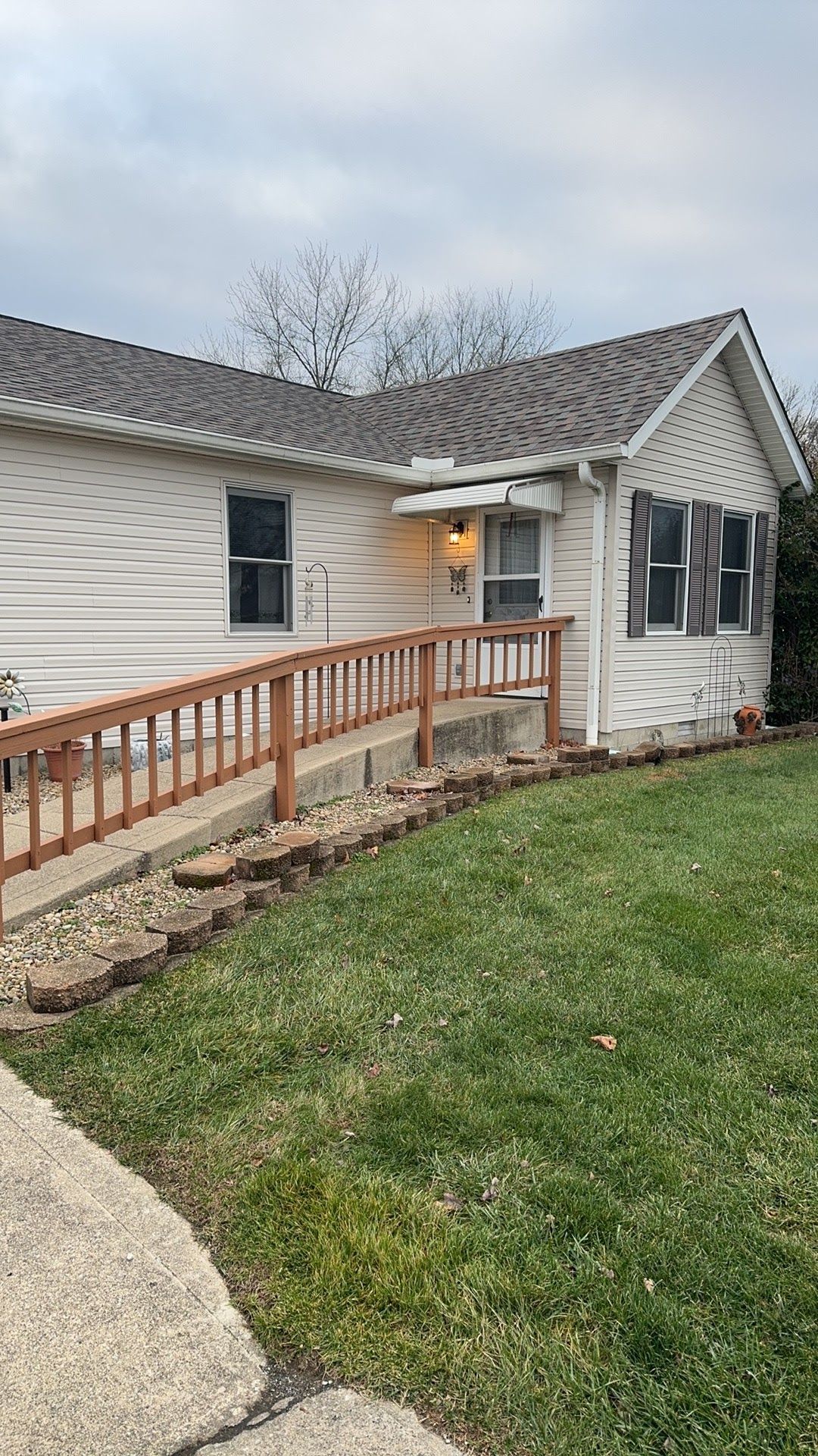 White house exterior with a wooden accessibility ramp leading to the front door and a small lawn.