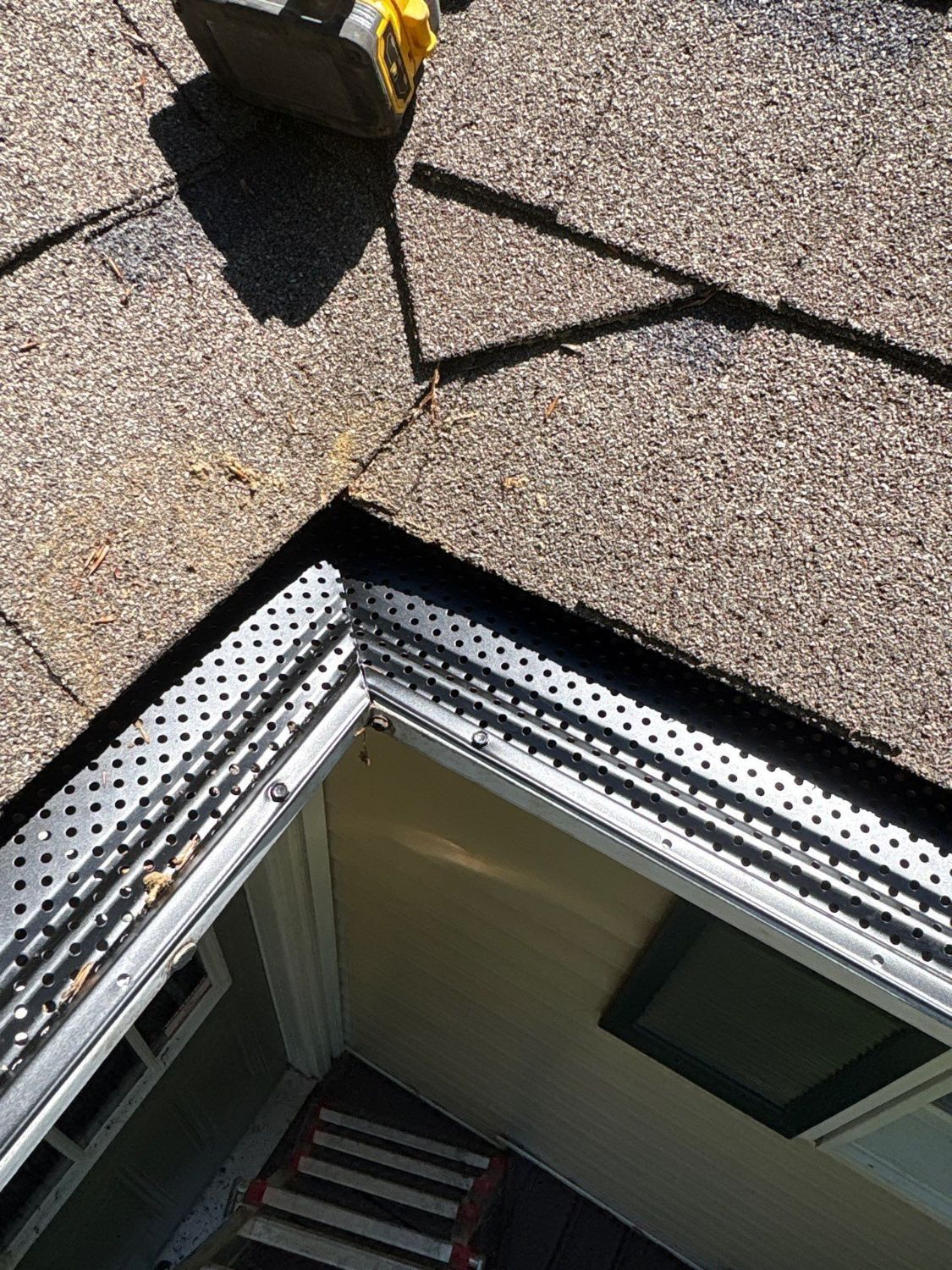 Perforated aluminum leaf guard fitted at a gutter corner
