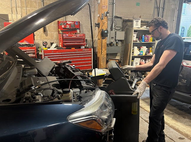 Expert technician in garage diagnosing vehicle with hood up in Melrose, MA | Certified Automotive Solutions