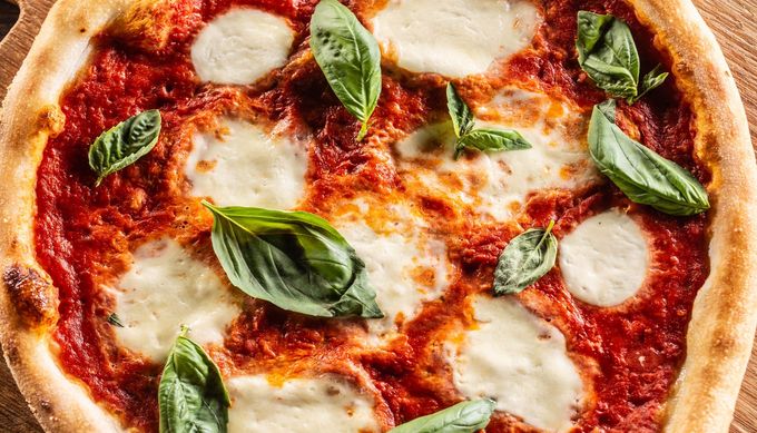 Pizza Margherita con foglie di basilico fresco e mozzarella fusa su una crosta croccante