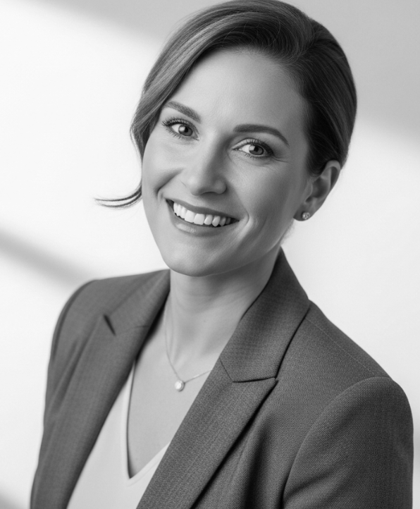 Smiling professional in a blazer, posed against a plain background.