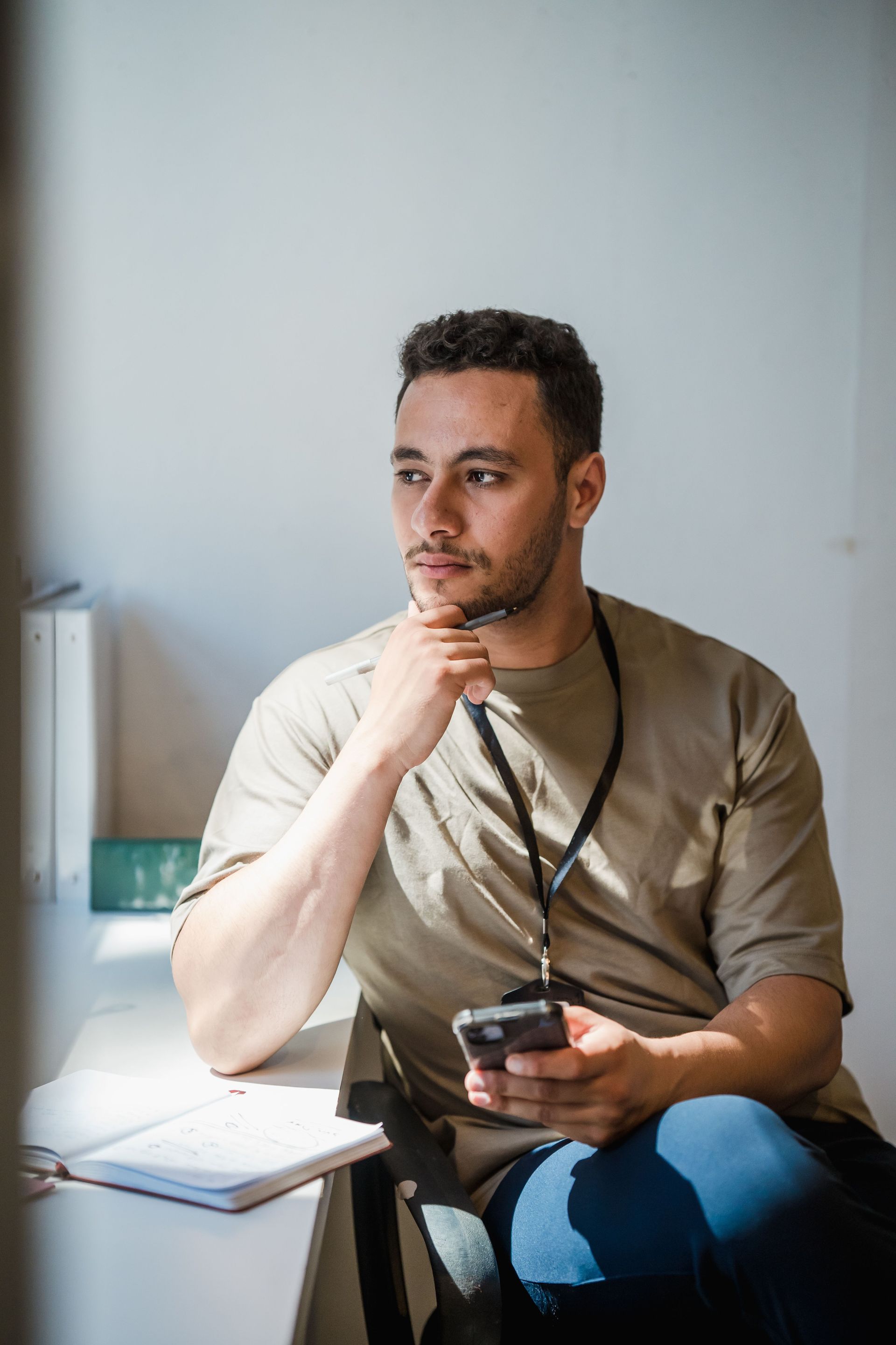 Person sitting by a window, holding a mug and gazing thoughtfully ahead.