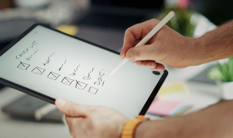 Hand using a stylus on a tablet showing sketch diagrams on a white screen