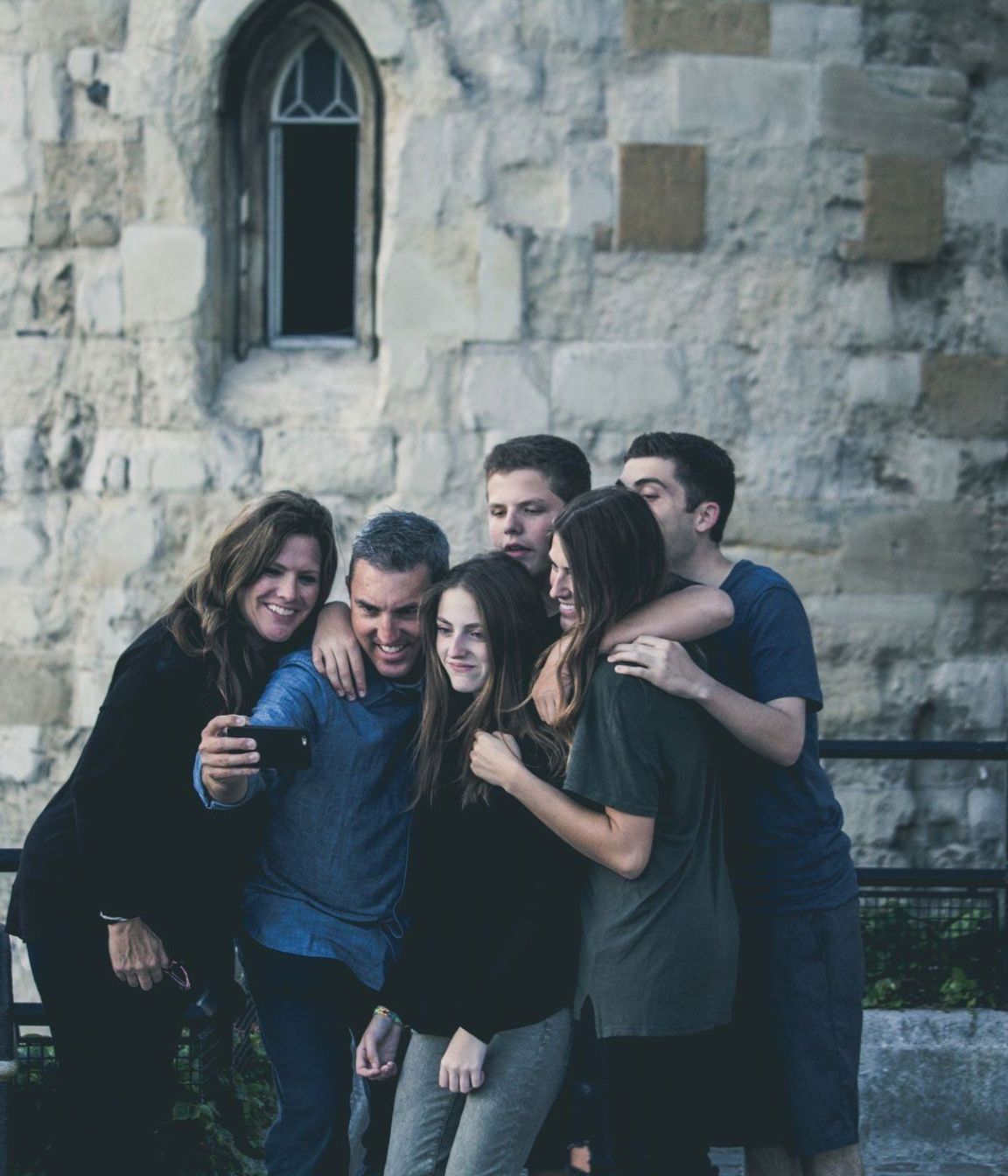 A family posing for a picture in front of a stone wall.