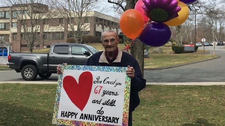 A man is holding a sign that says happy anniversary