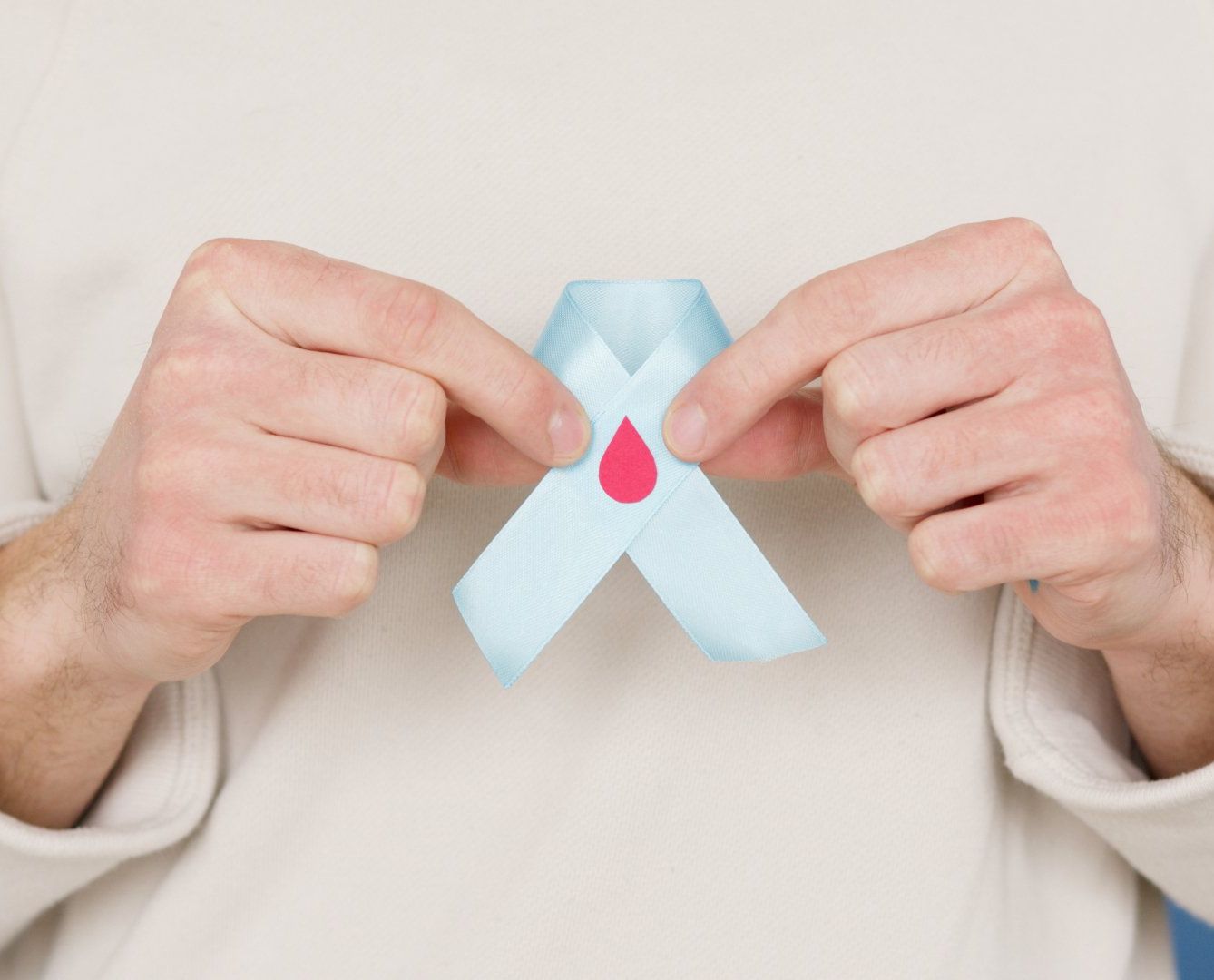 A man is holding a blue ribbon with a red drop on it