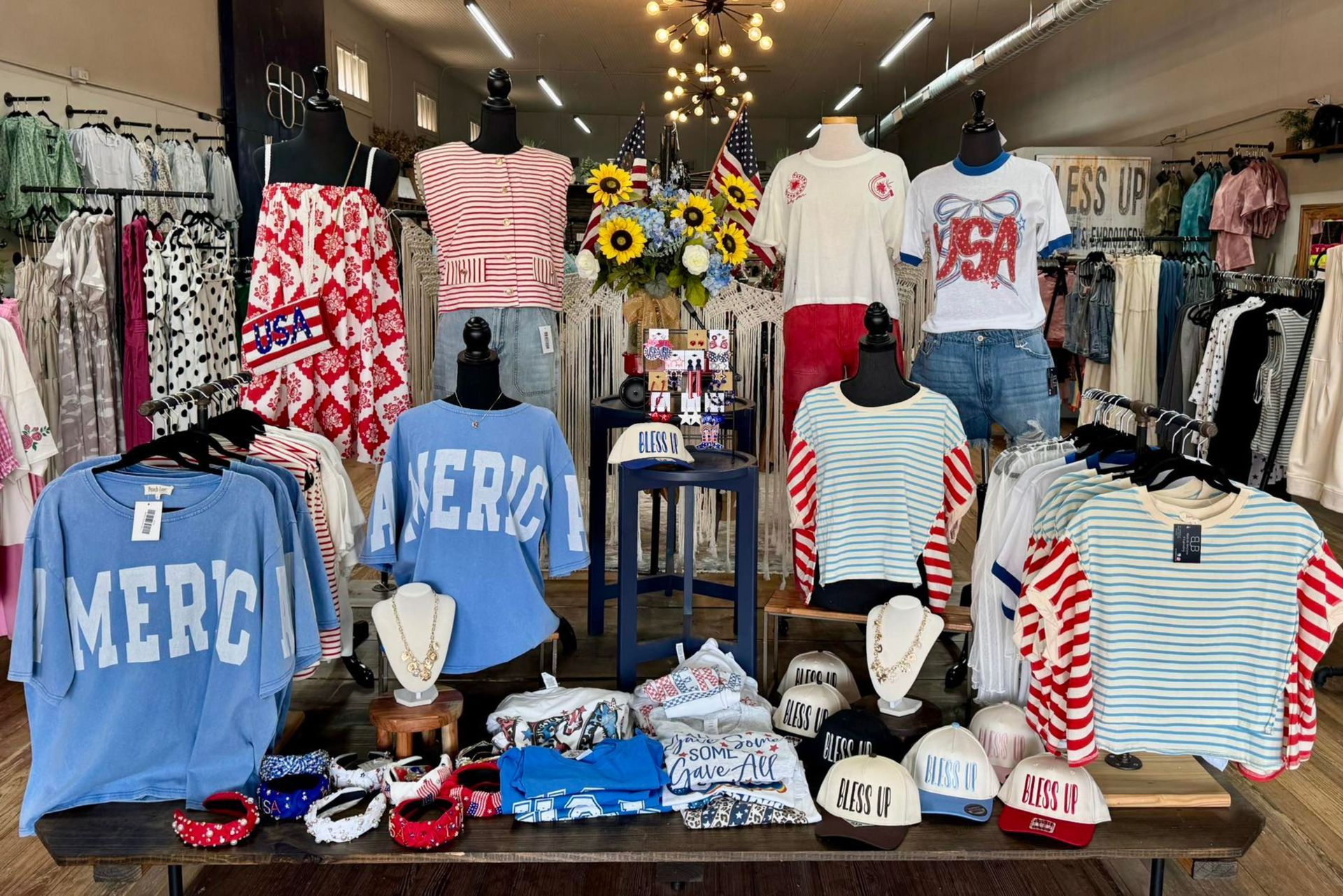 A clothing store display featuring shirts, hats, and accessories with a patriotic red, white, and blue theme.