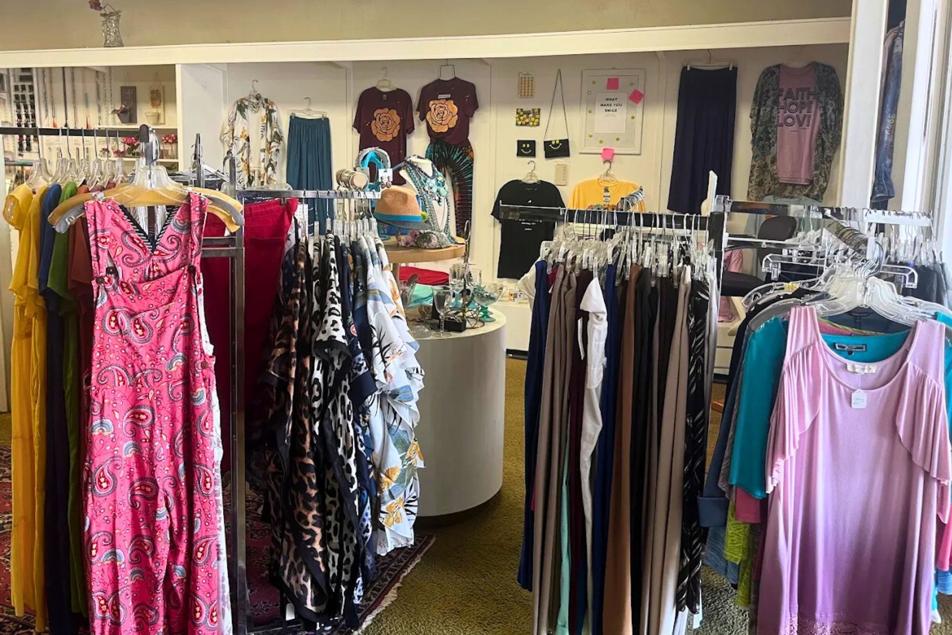 Clothing racks filled with dresses and shirts in a brightly lit boutique shop.