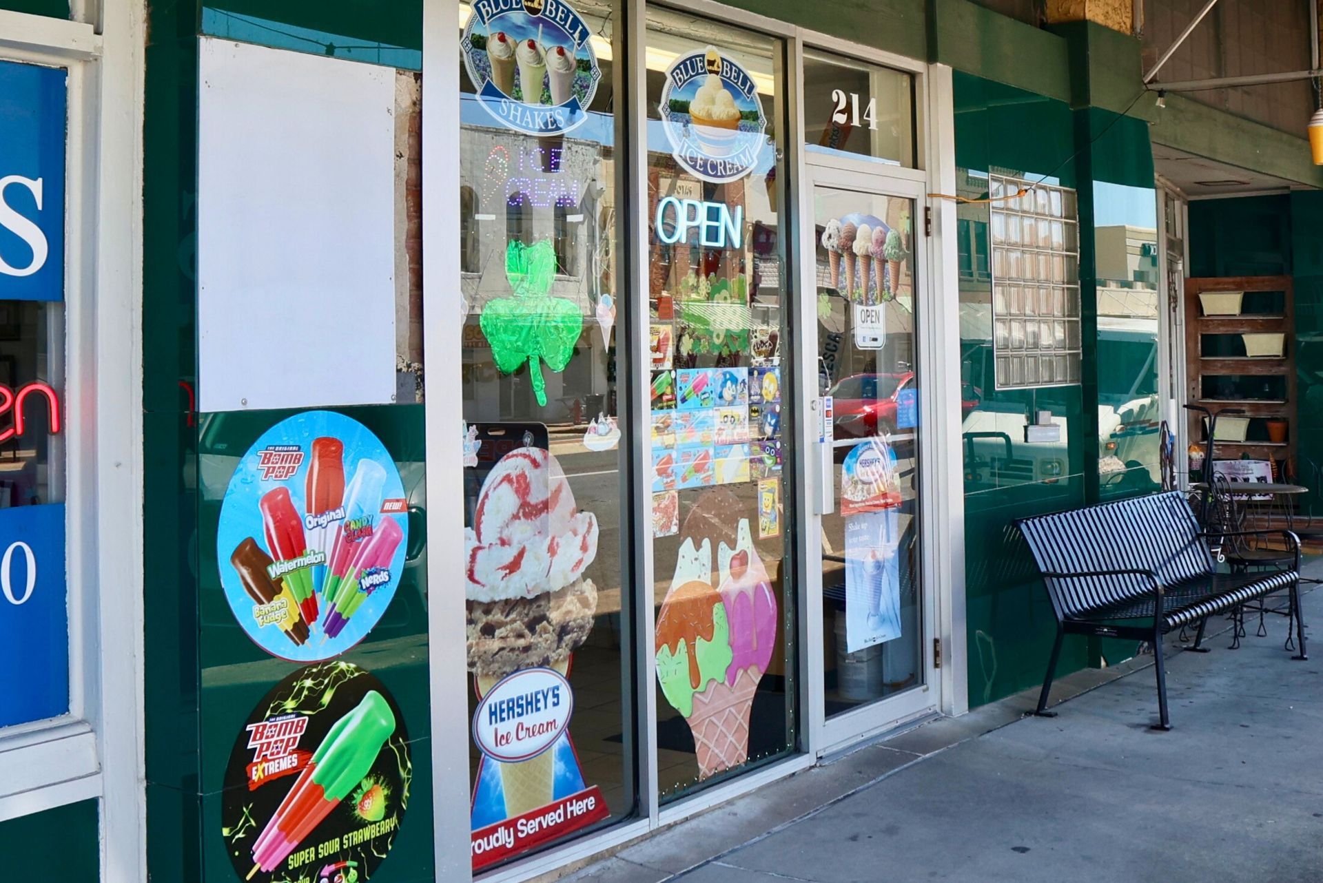 A storefront for an ice cream shop with green walls, glass doors, and window decals showing ice cream and popsicles.