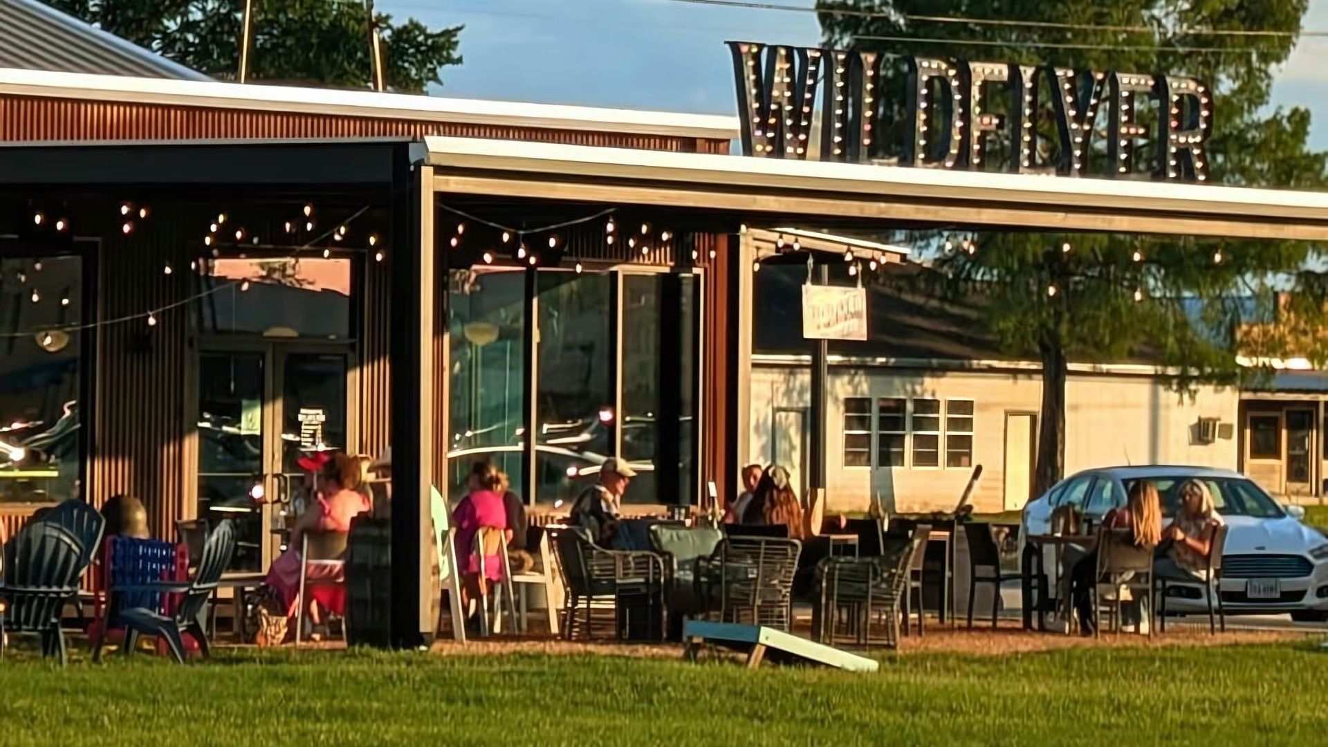 People sitting at tables on an outdoor patio at a restaurant named