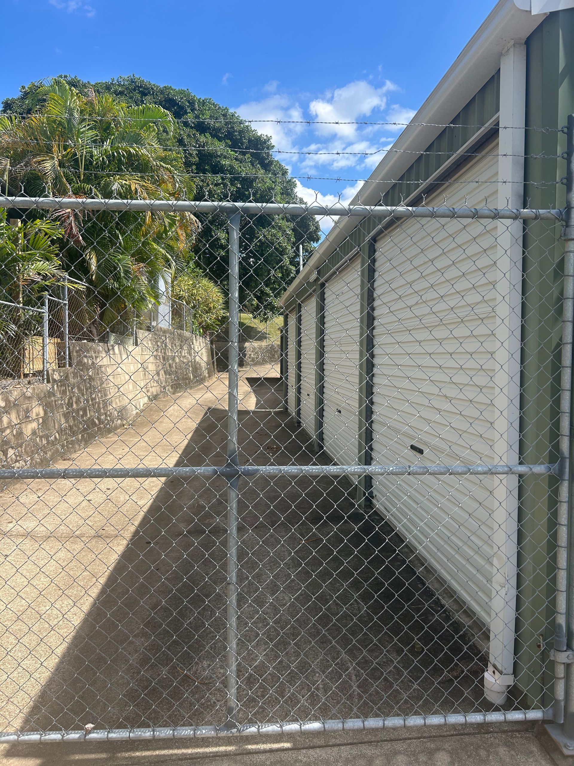 Chain-link fence in front of a row of white storage units — Gympie Mini Storage in Gympie, QLD