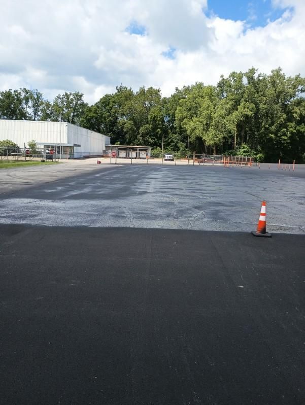 Image of a sealcoating service  with workers at a community parking lot in Fort Wayne, IN.
