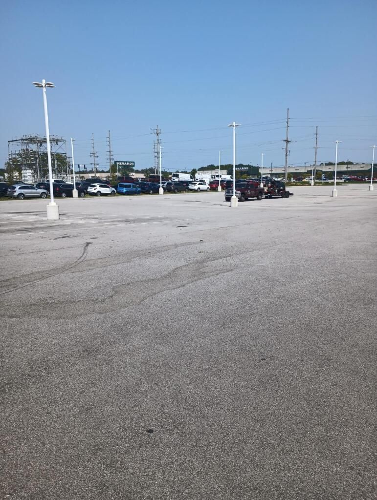 Image of A close-up view of sealcoat being sprayed onto a parking lot pavement in Fort Wayne, IN, to protect and rejuvenate the surface.
