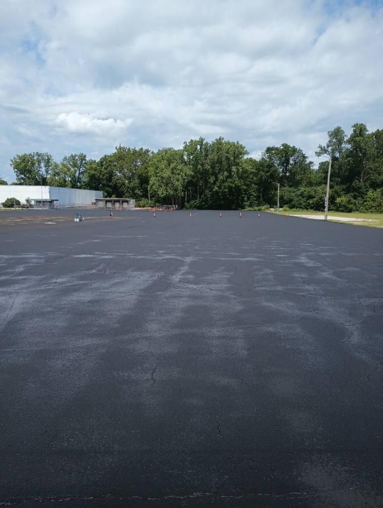 Image of Sealcoat application you can see Midwest Seal Team crew workers applying sealcoat to a parking lot in Fort Wayne, IN.
