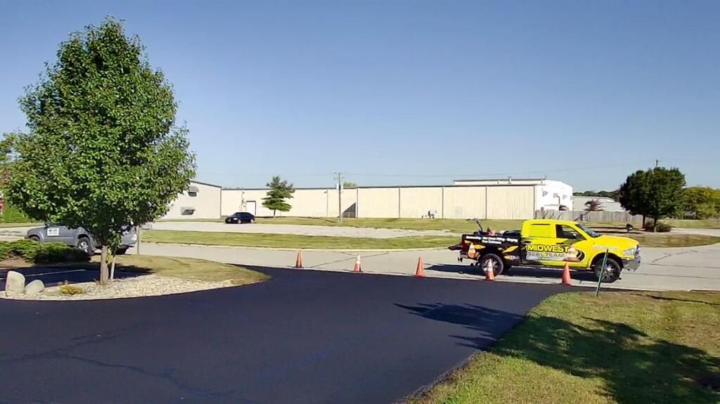 Image of a freshly sealcoated driveway in Fort Wayne, IN. You can see a newly sealed  driveway, with a smooth, glossy surface 
