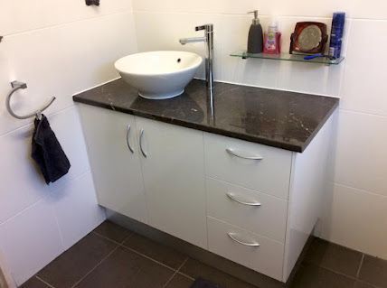 A Bathroom Vanity With a Sink and a Black Counter Top — De Rose Plumbing In Bayview Heights, QLD