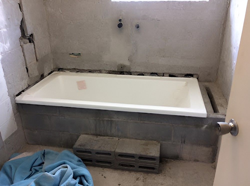 A Bathtub is Sitting in a Bathroom Next to a Door — De Rose Plumbing In Bayview Heights, QLD