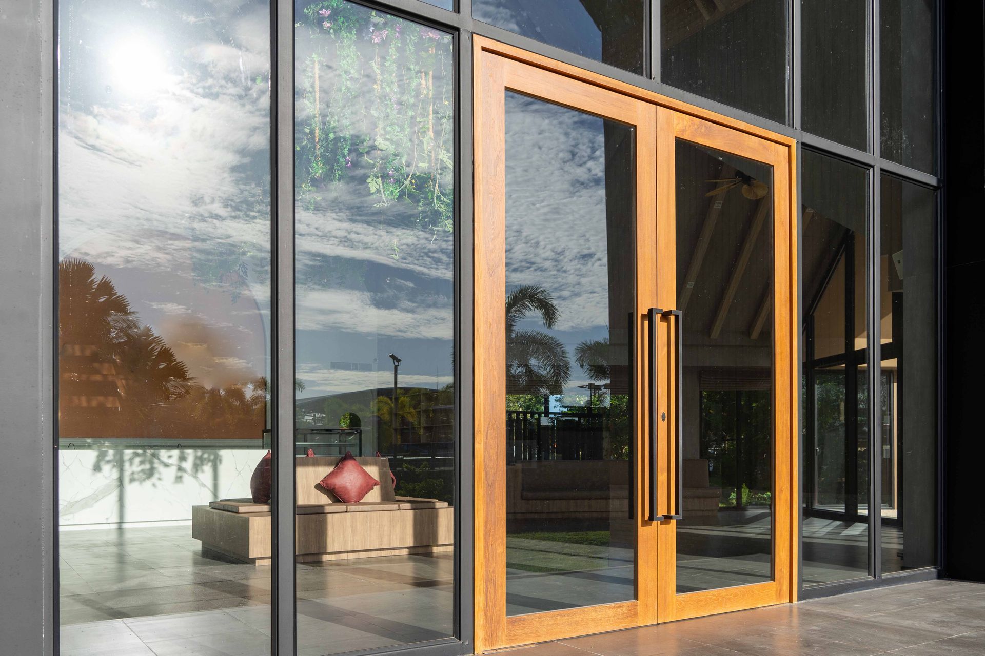 Les doubles portes vitrées en bois reflètent le paysage extérieur ; entrée du bâtiment.