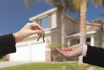 Handing over house keys in front of a suburban home