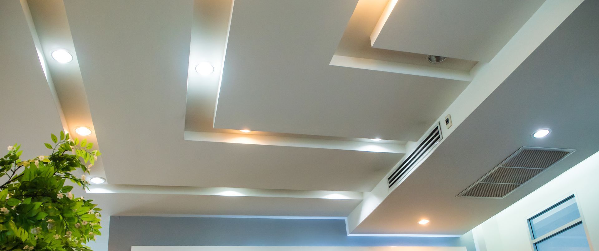 Plafond encastré blanc avec éclairage et bouches d'aération.
