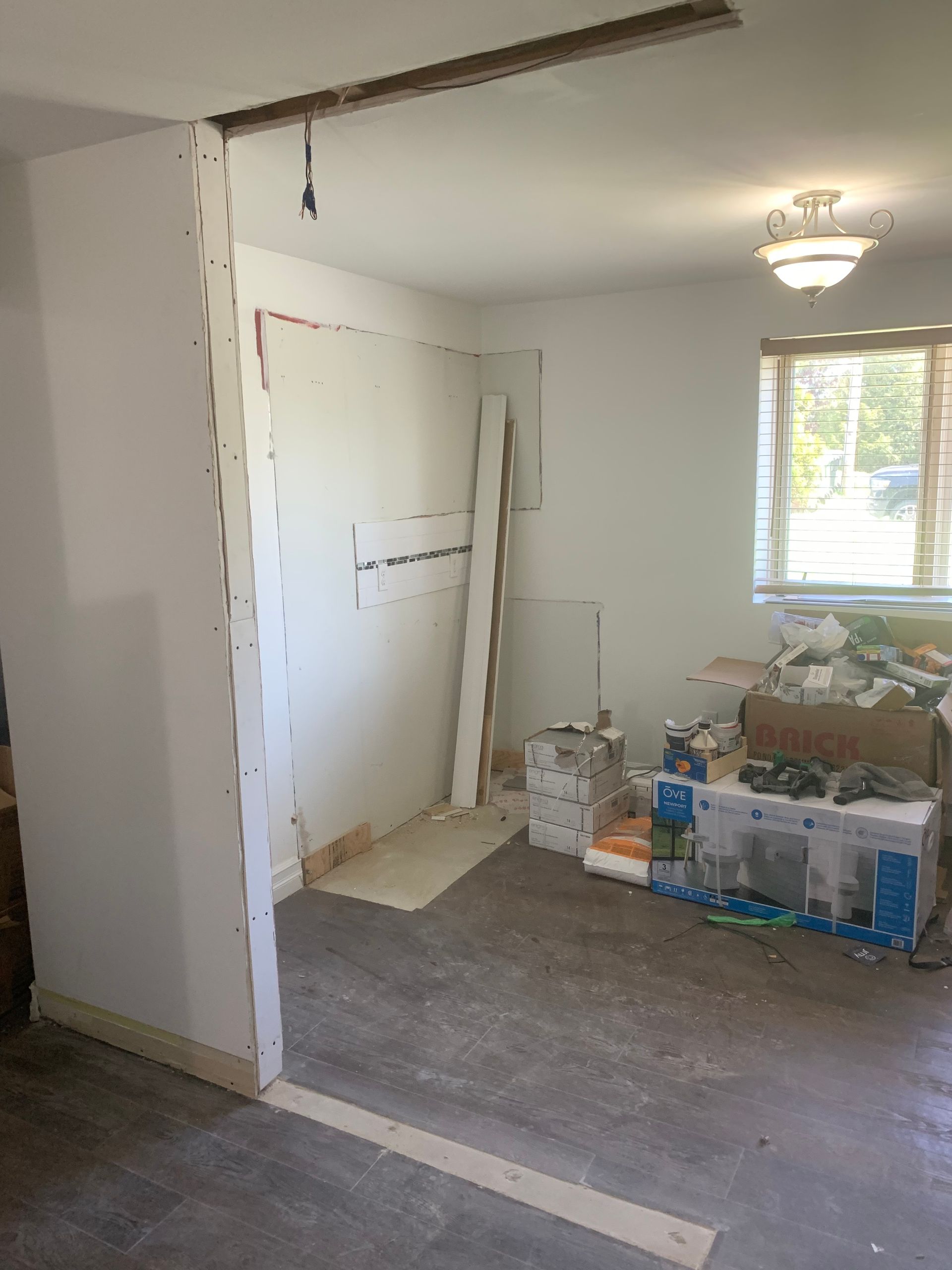 Pièce intérieure en cours de rénovation, avec charpente apparente, cloisons sèches partielles et débris au sol.