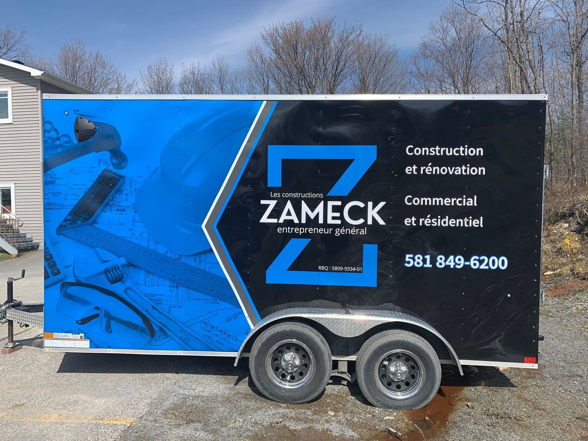 Remorque noire avec logo bleu indiquant « ZAMEČK » et numéro de téléphone.