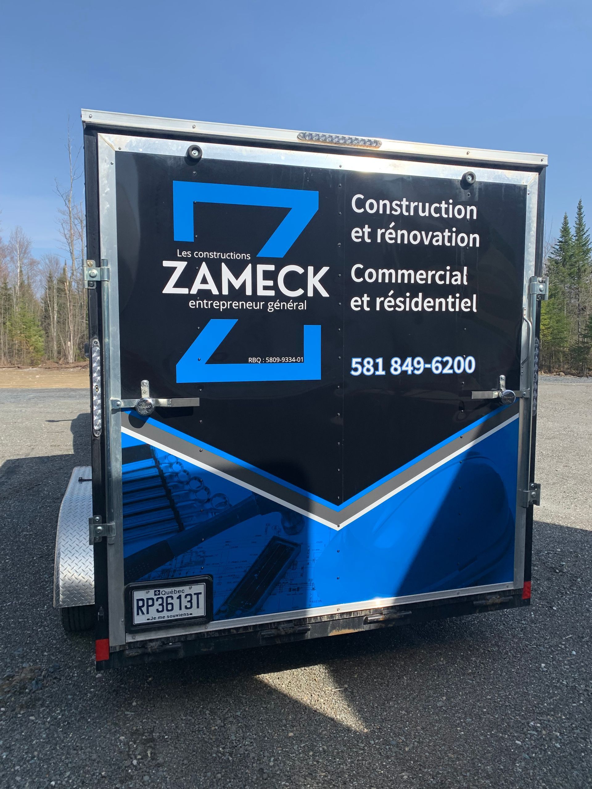 Remorque noire avec logo « ZAMECK », signalétique d'entreprise de construction. Touches bleues et grises, numéro de téléphone visible.