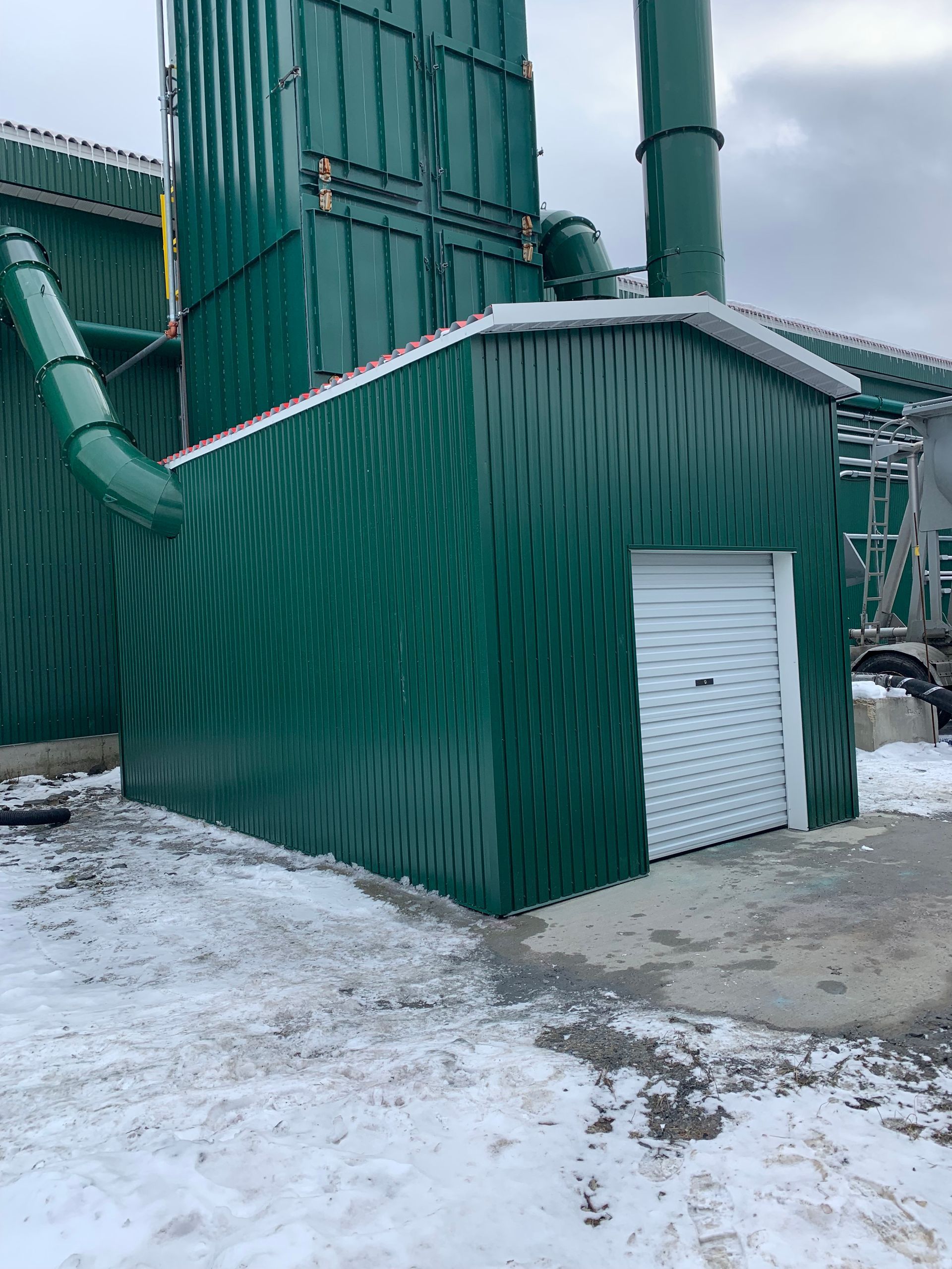 Bâtiment industriel écologique avec un petit hangar et de la neige au sol.