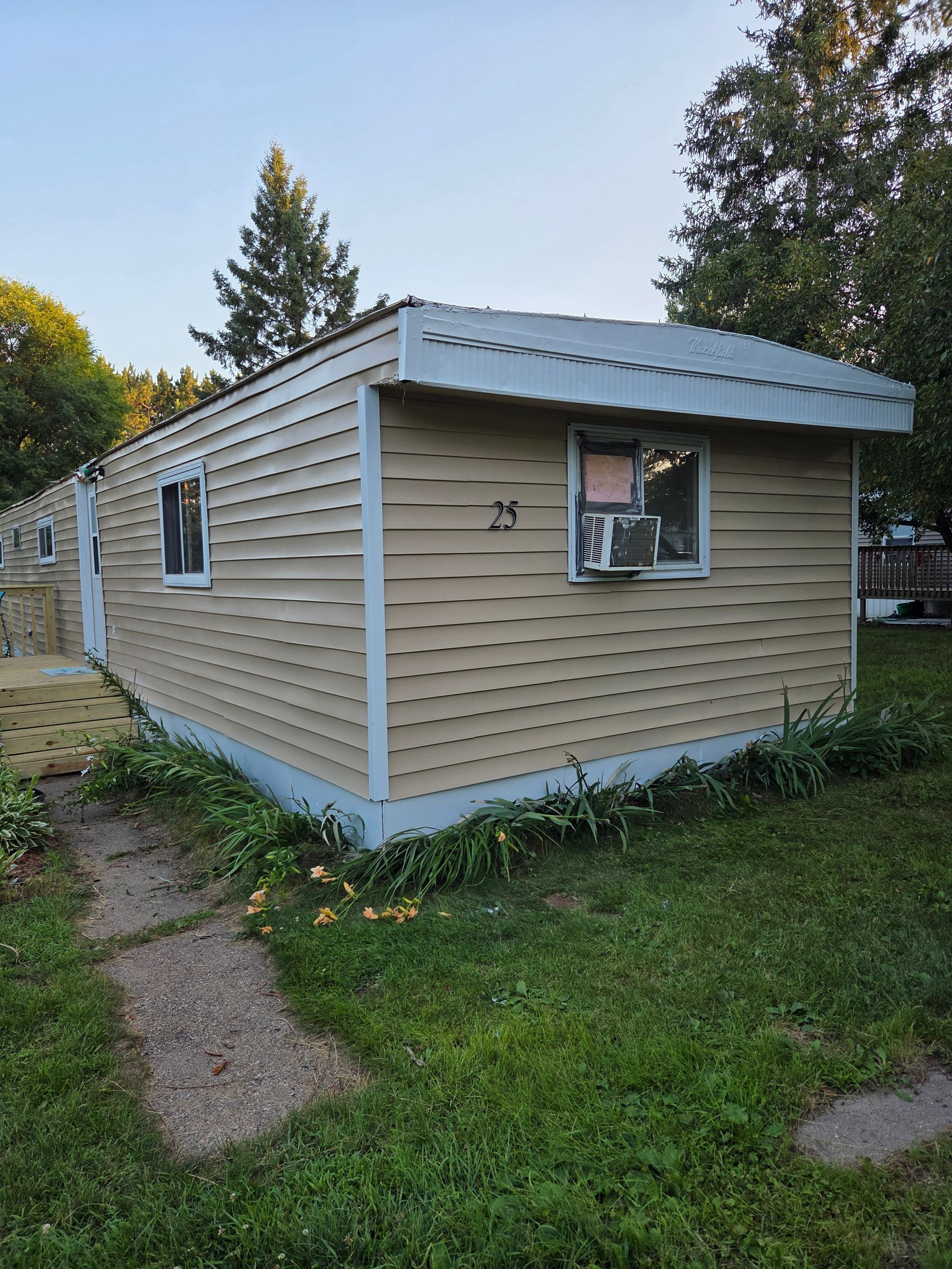 Small beige shed with white trim and a slanted roof in a grassy yard.