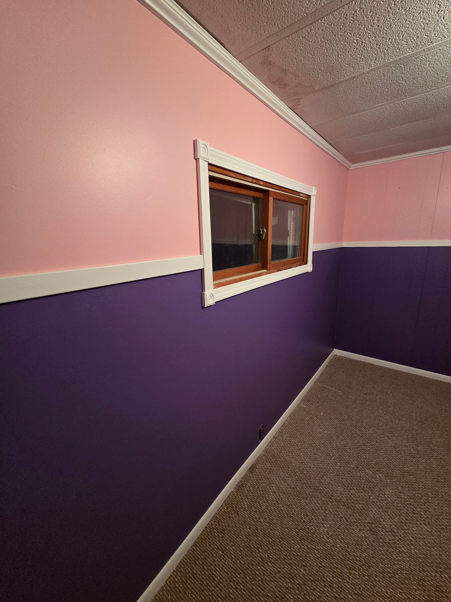 Purple and pink empty room with a small window and sloped ceiling