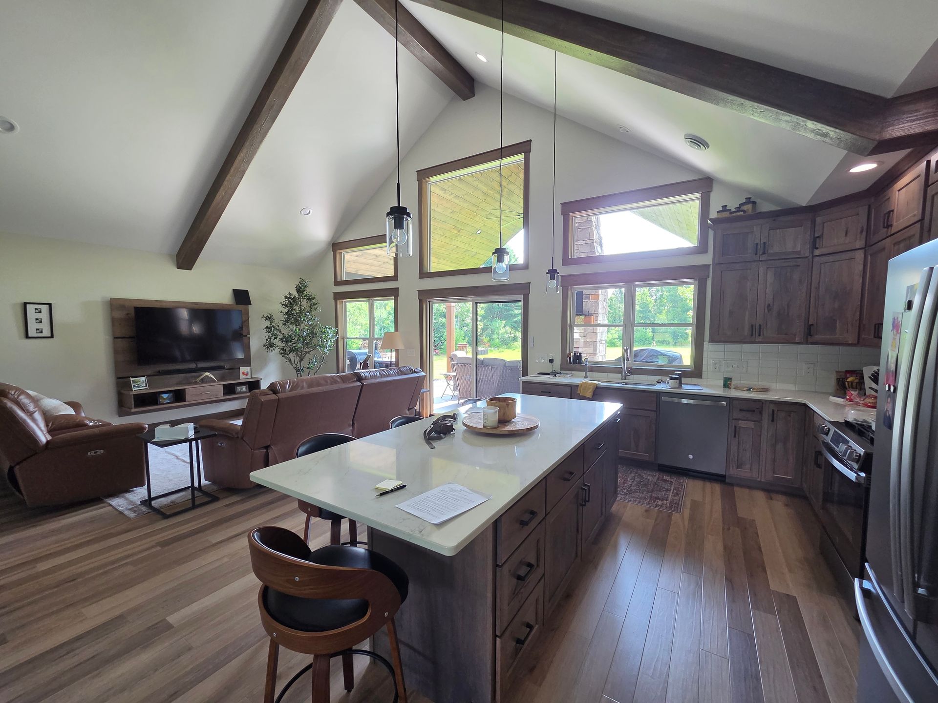 Bright open kitchen with a central island, wood cabinets, large windows, and vaulted ceiling