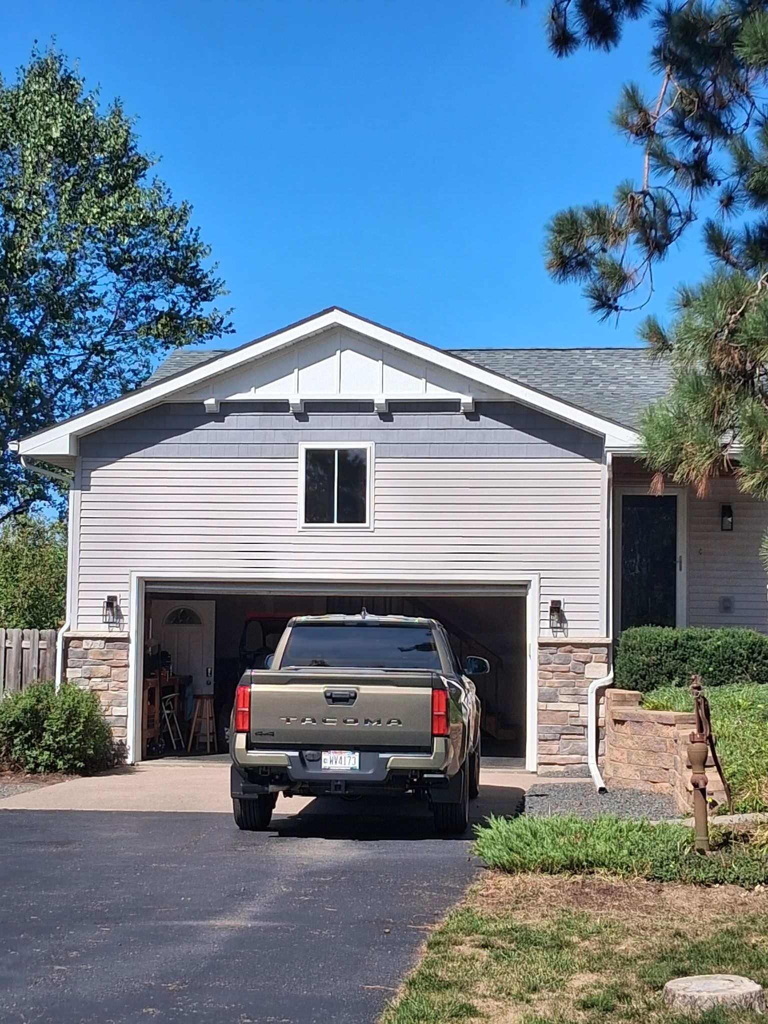 White suburban house with open garage and a pickup truck parked in the driveway under a clear blue sky
