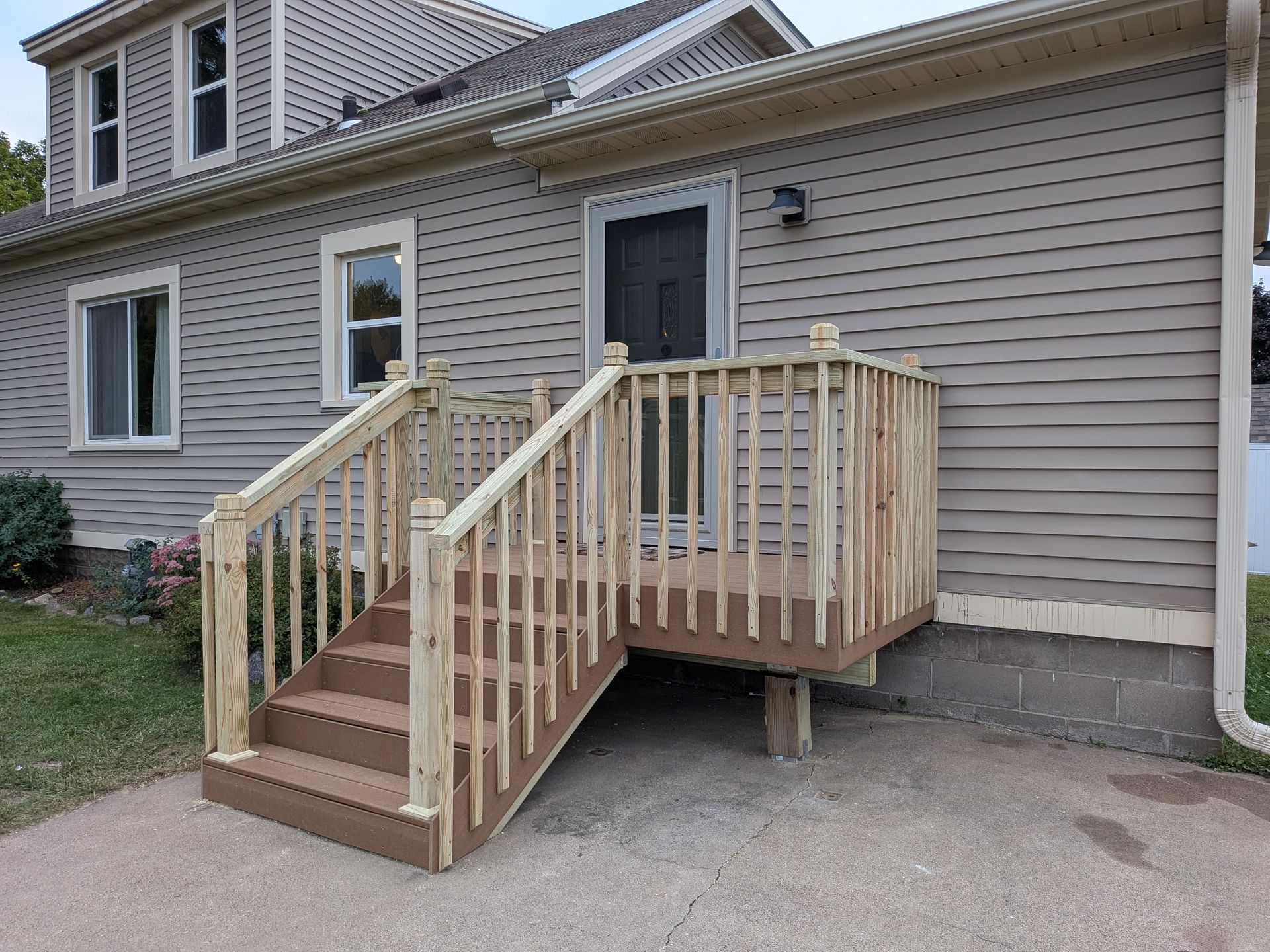 Wooden accessibility ramp and steps leading to a house entrance with tan siding.
