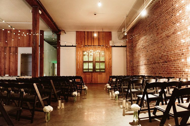 A row of folding chairs are lined up in a room with a brick wall.