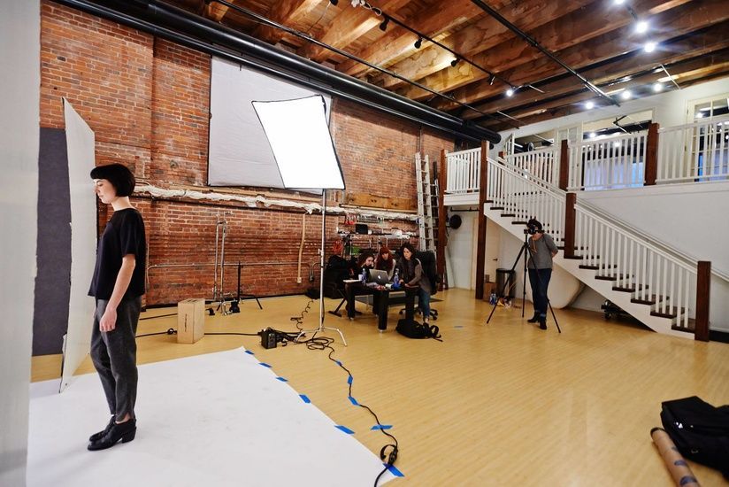 A woman is standing in front of a camera in a photo studio.