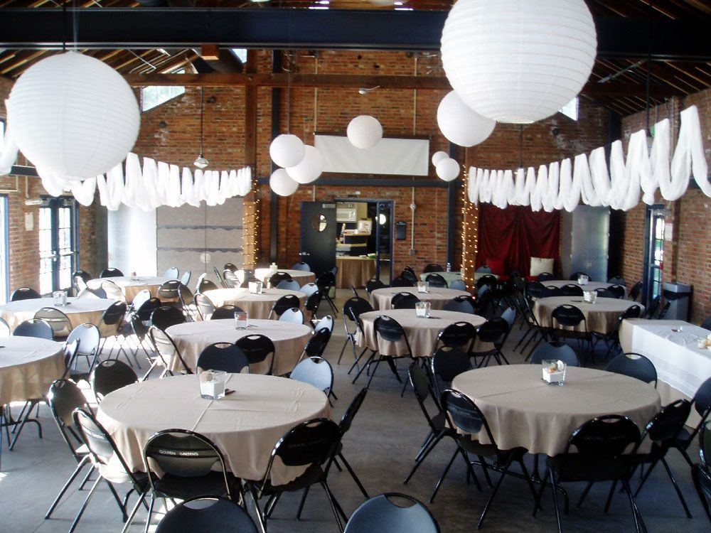 A large room with tables and chairs and lanterns hanging from the ceiling