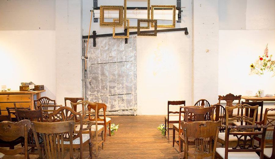A room filled with chairs and tables and a wall with frames on it.