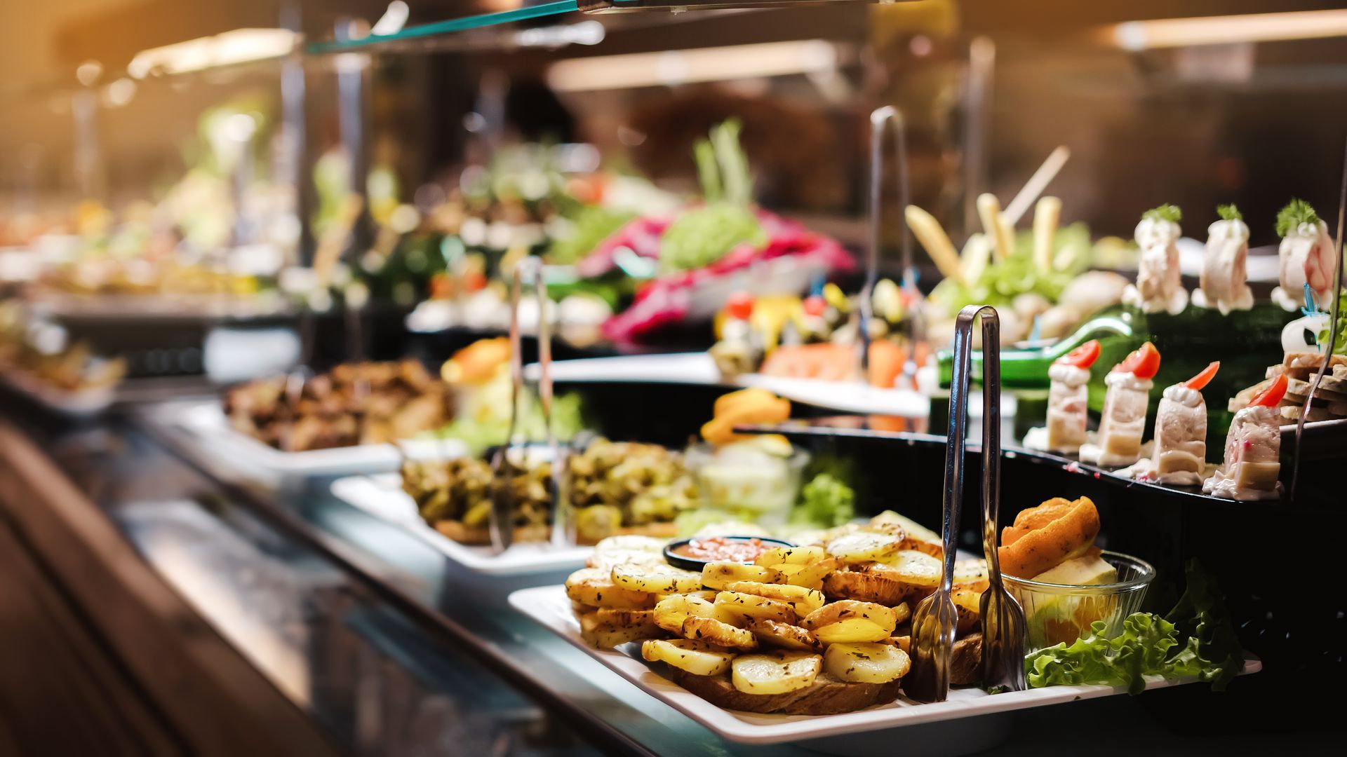 A buffet line filled with lots of food and tongs.