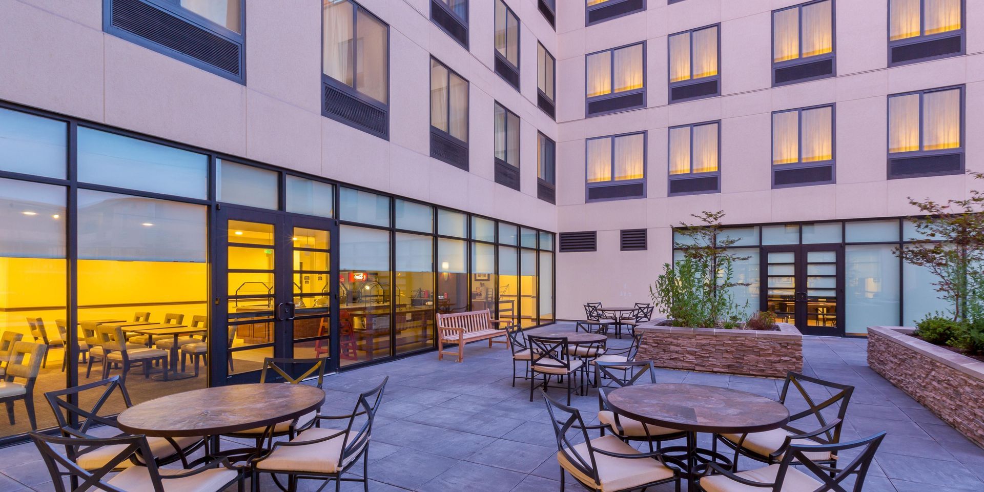 A patio with tables and chairs in front of a large building.
