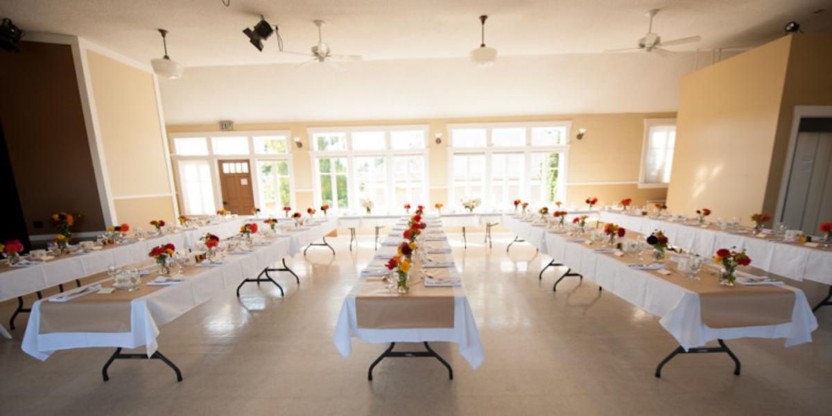 A large room with tables and chairs set up for a wedding reception.